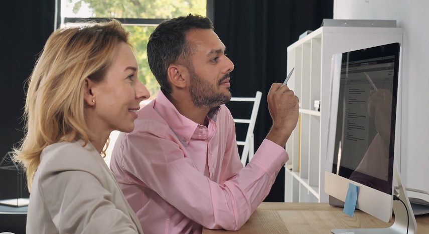 in a business office, man and woman look at computer screen